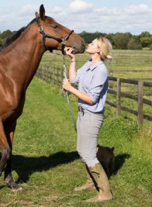 Girl with brown horse in field